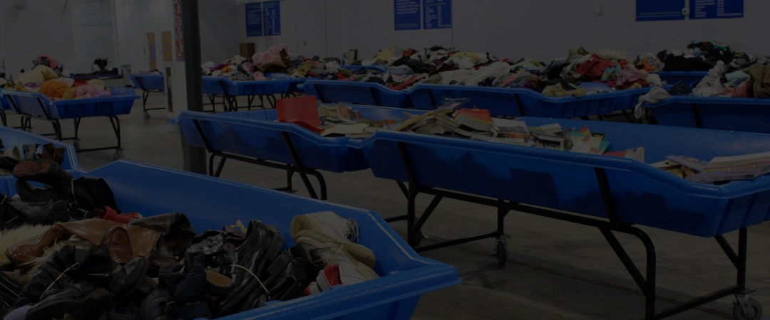 Interior of a Goodwill Bins outlet store with shoppers searching through large bins.